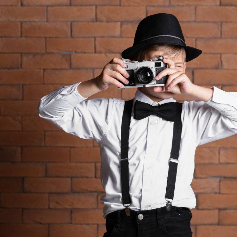 Cute,Little,Detective,Taking,Photo,Against,Brick,Wall