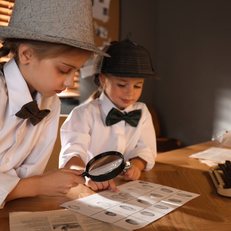 Cute,Little,Detectives,Exploring,Fingerprints,With,Magnifying,Glasses,At,Table